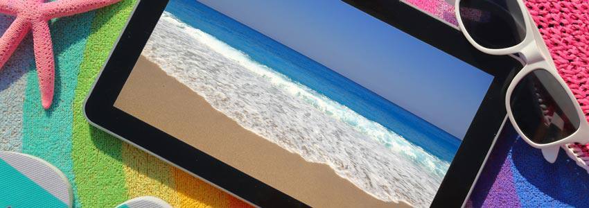 A tablet on top of colorful sand with a picture of a beach