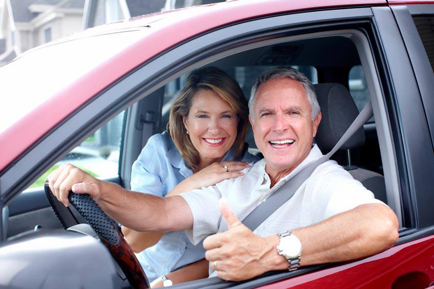 Two people in a car with the driver giving a thumbs up