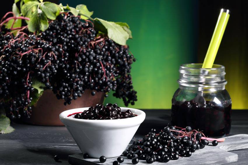 Elderberries being crushed inside of a jar on top of a table