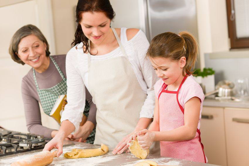 A family helping the daughter cook with dough 