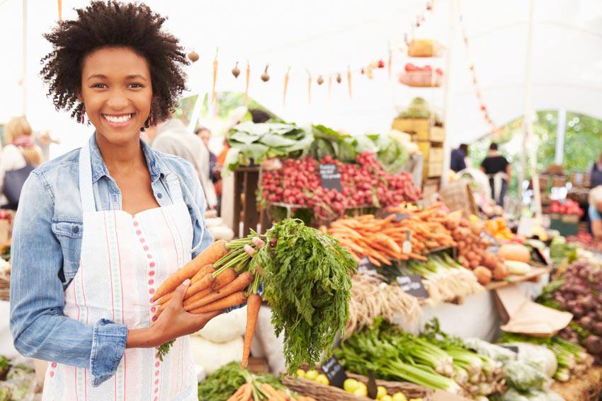 A woman at a food market holding carrots