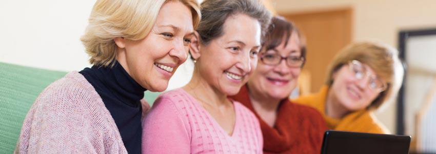 Four elderly women using a computer