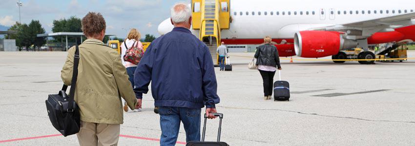 An elderly couple on their way to the airplane with their luggage