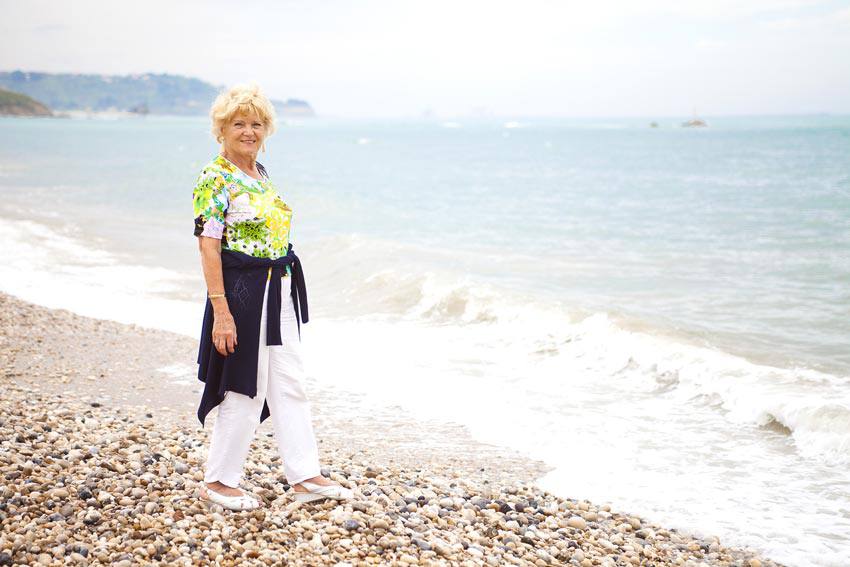 An elderly woman standing on the beach