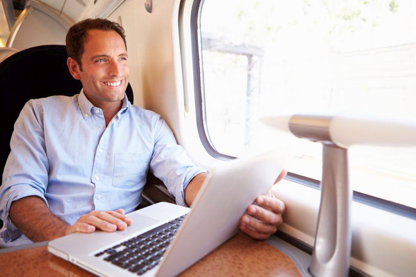 A man on his computer while riding a train