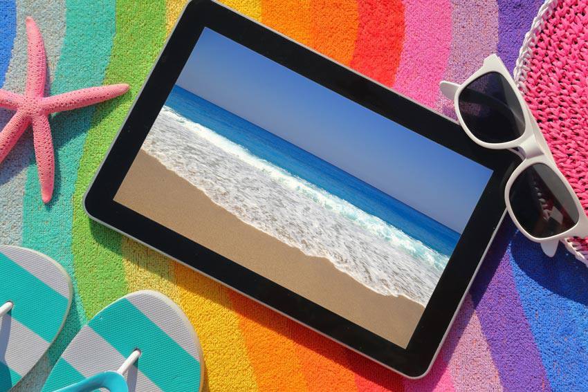 A tablet on top of colorful sand with a picture of a beach