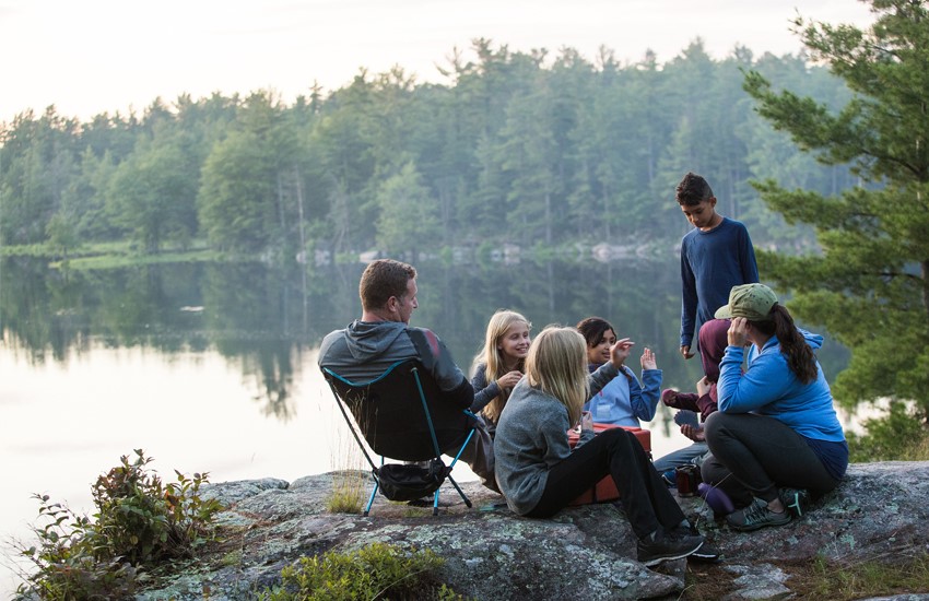 A group of people camping on the side of a lake