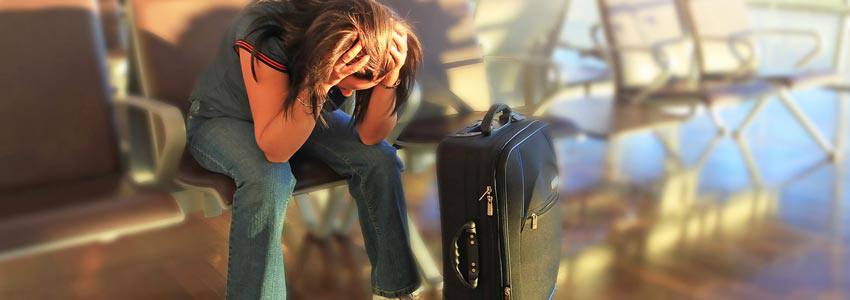 A woman sitting at the airport with their hands on their head 