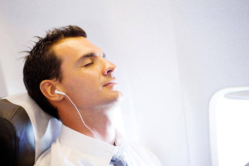 A man sleeping on an airplane while listening to music