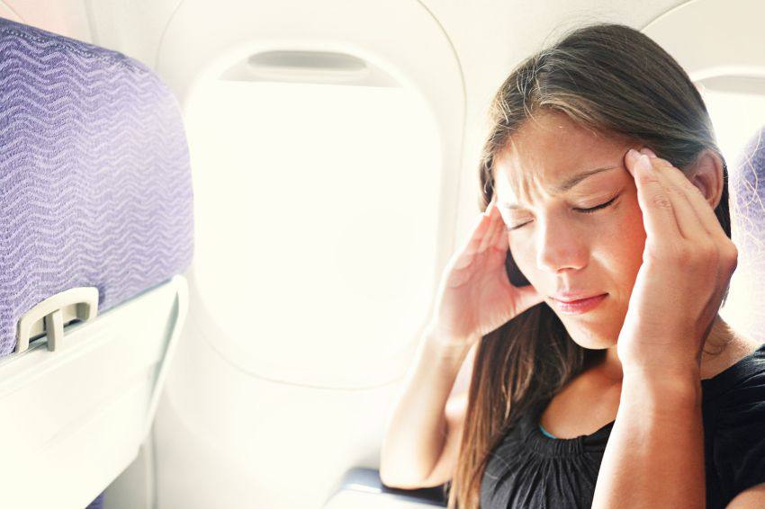 A woman has a headache while in an airplane