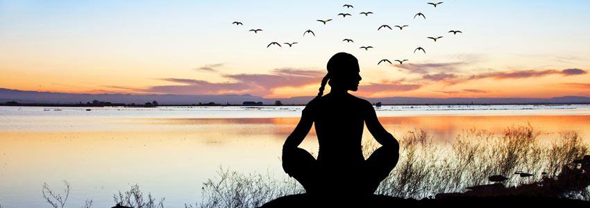 A woman meditating on the border of a lake 