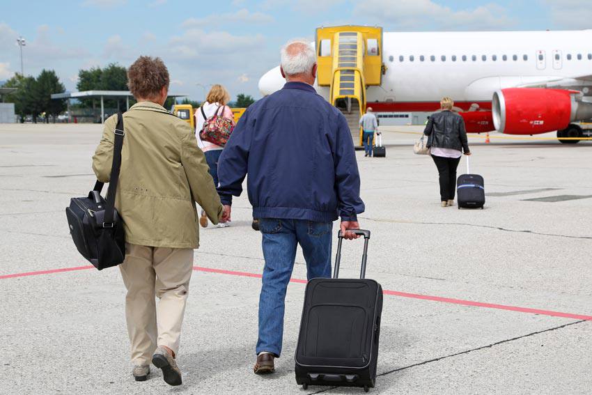 An elderly couple on their way to the airplane with their luggage
