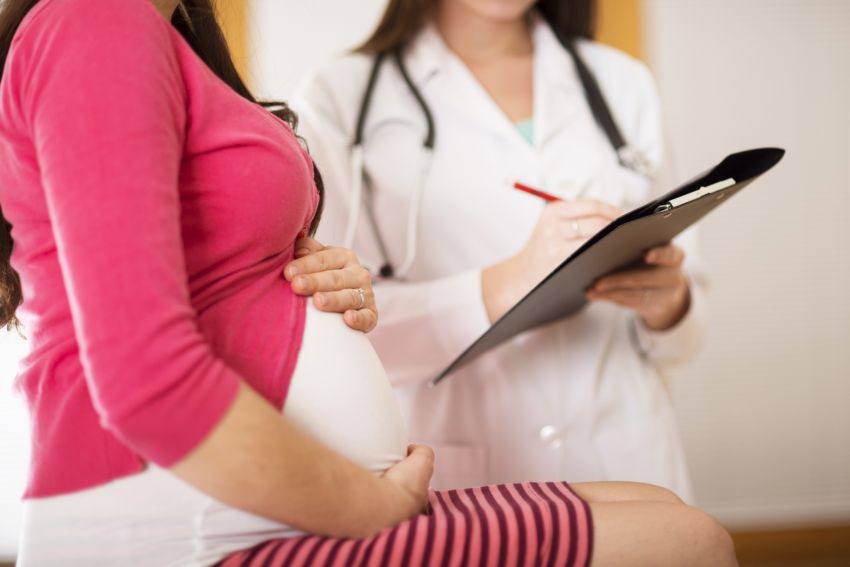 A pregnant woman and her doctor writing on a pad