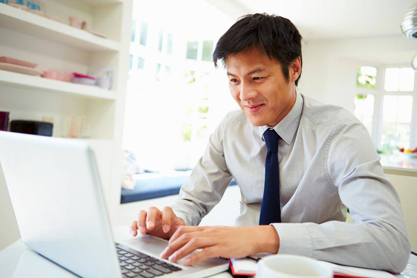 A happy man using his computer inside his house