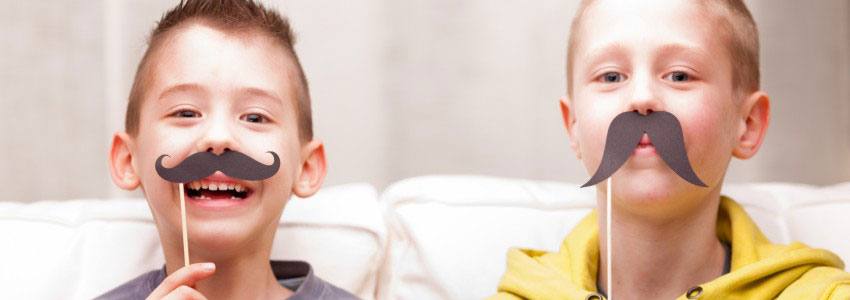 Two children playing with fake mustaches 
