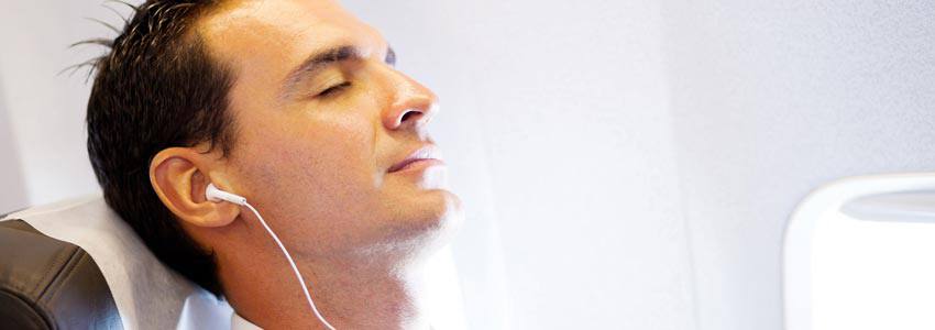 A man sleeping on an airplane while listening to music