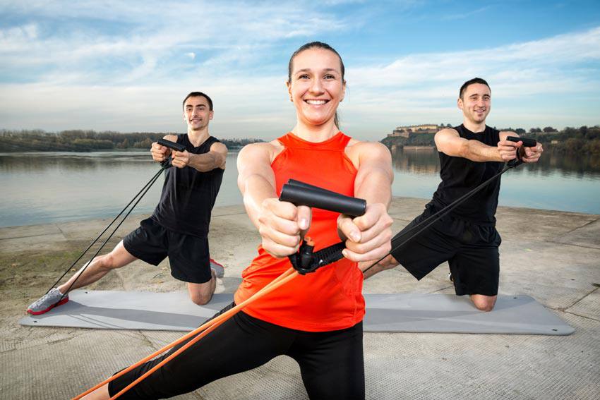 Three people training with tension cords outside