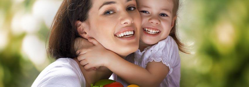 A mother with her daughter holding a basket of fresh vegetables