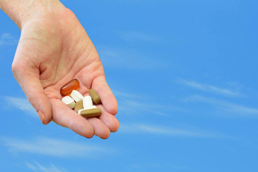 A hand full of pills with different colours
