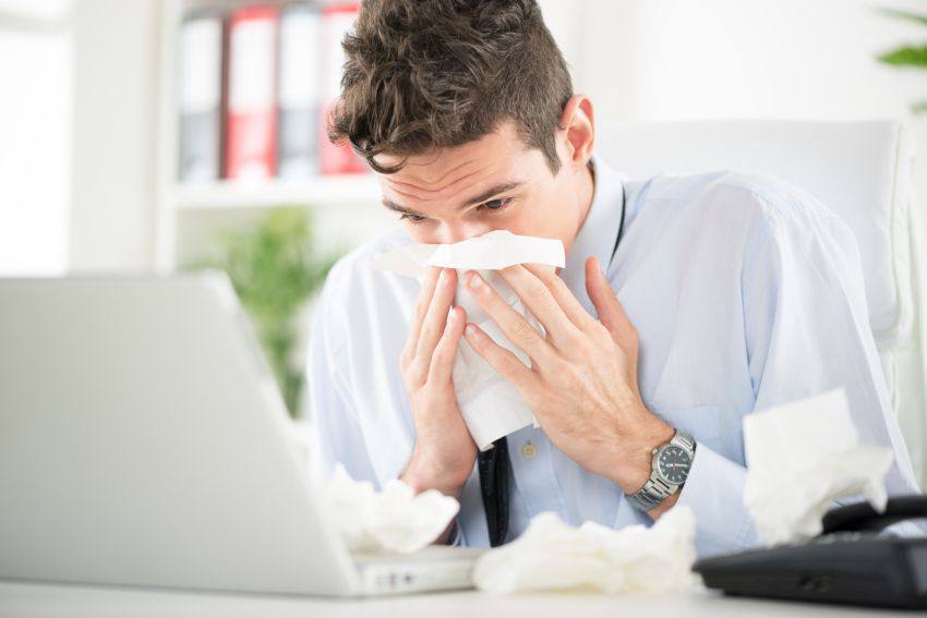 Office worker sneezing from cold