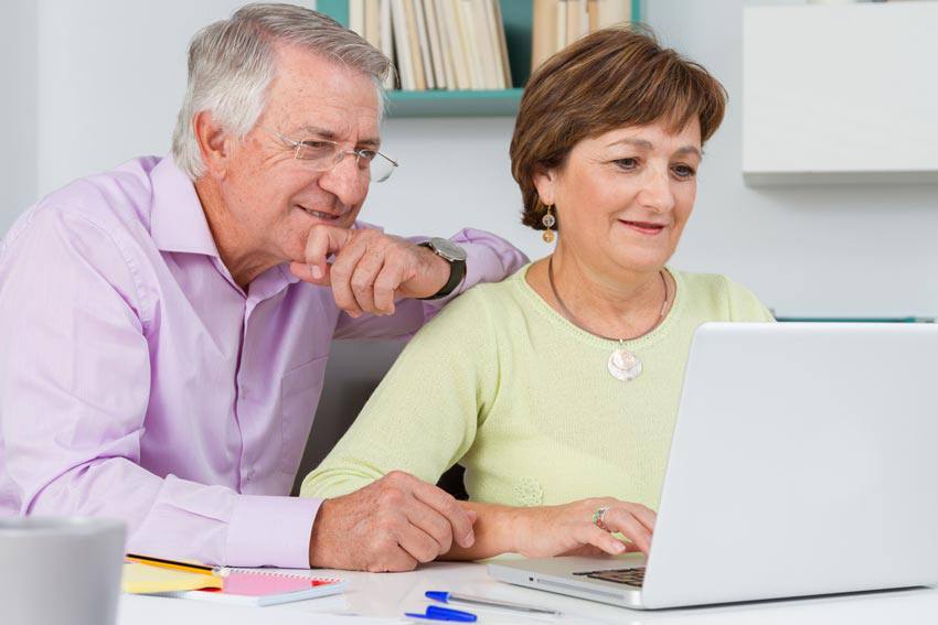 An elderly couple using their computer to travel