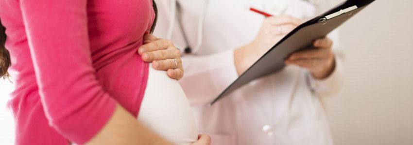 A pregnant woman and her doctor writing on a pad