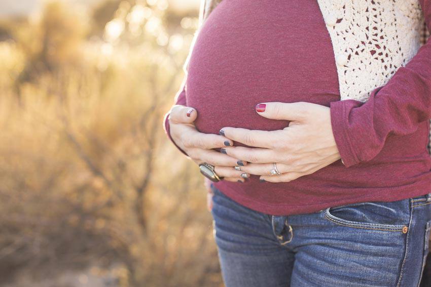 Pregnant women holding her belly with her two hands