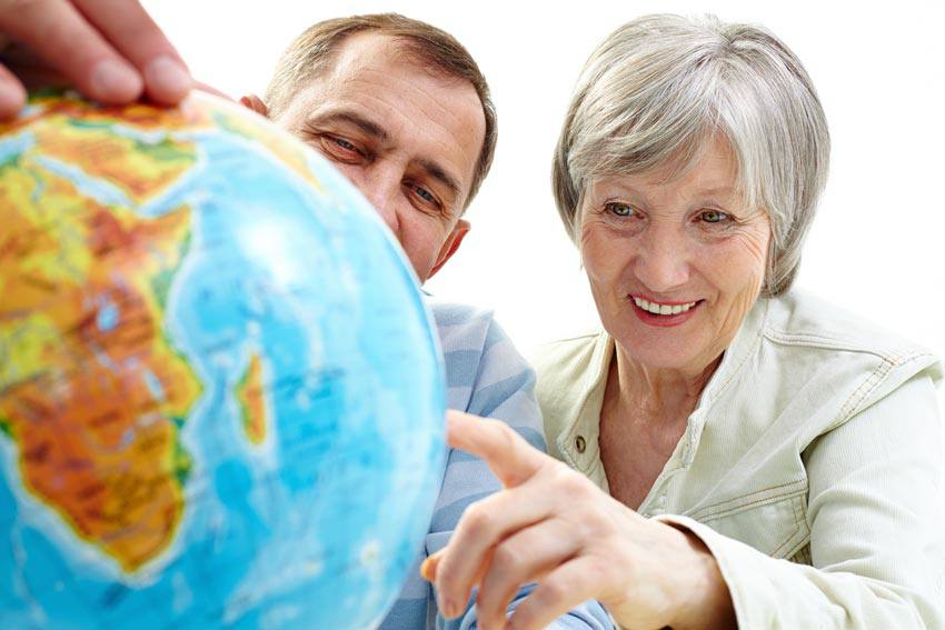 Two elderly people pointing at the world globe