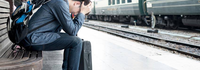 A sad person sitting on a bench at a train station