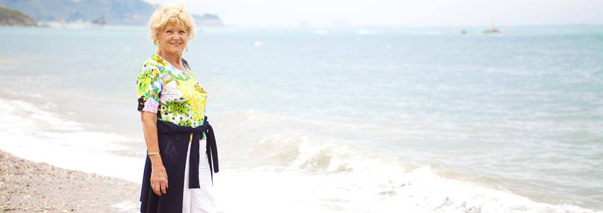 An elderly woman standing on the beach