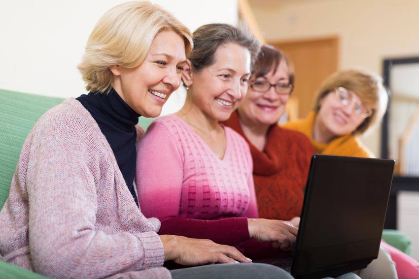 Four elderly women using a computer