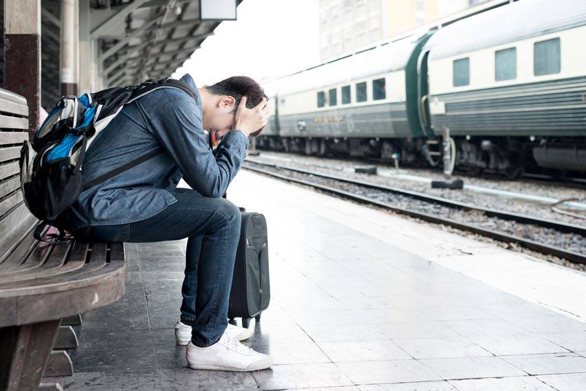 A sad person sitting on a bench at a train station