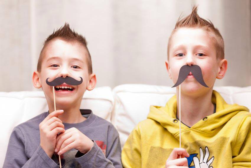 Two children playing with fake mustaches 